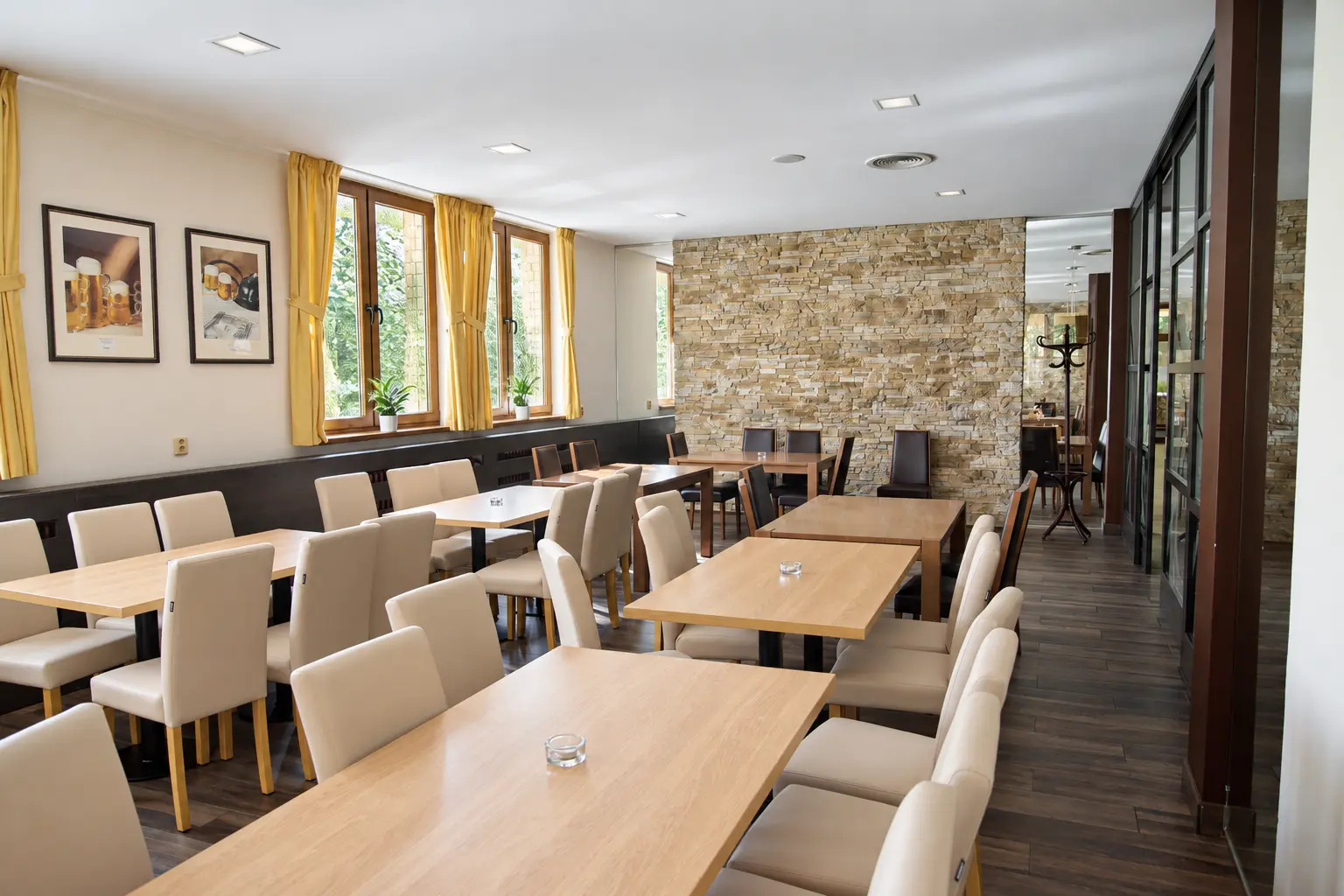 Prosvětlený sál restaurace Jadran se světlými židlemi
